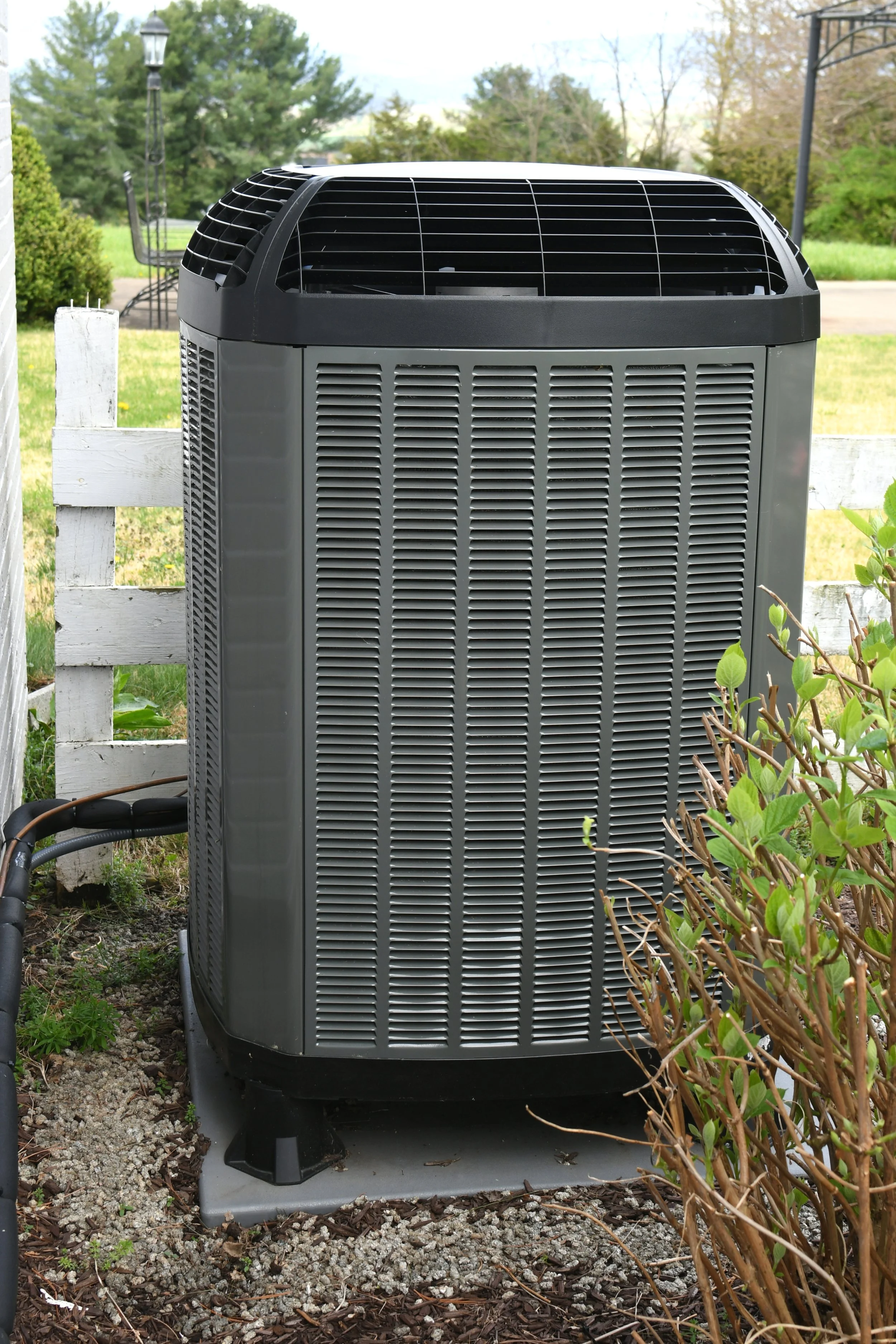 Residential central air conditioning condenser installed outside a home Replace