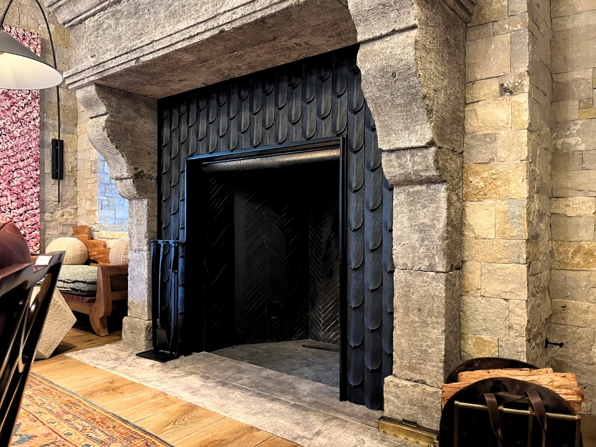 Custom black sheet metal fireplace surround installed in a stone fireplace