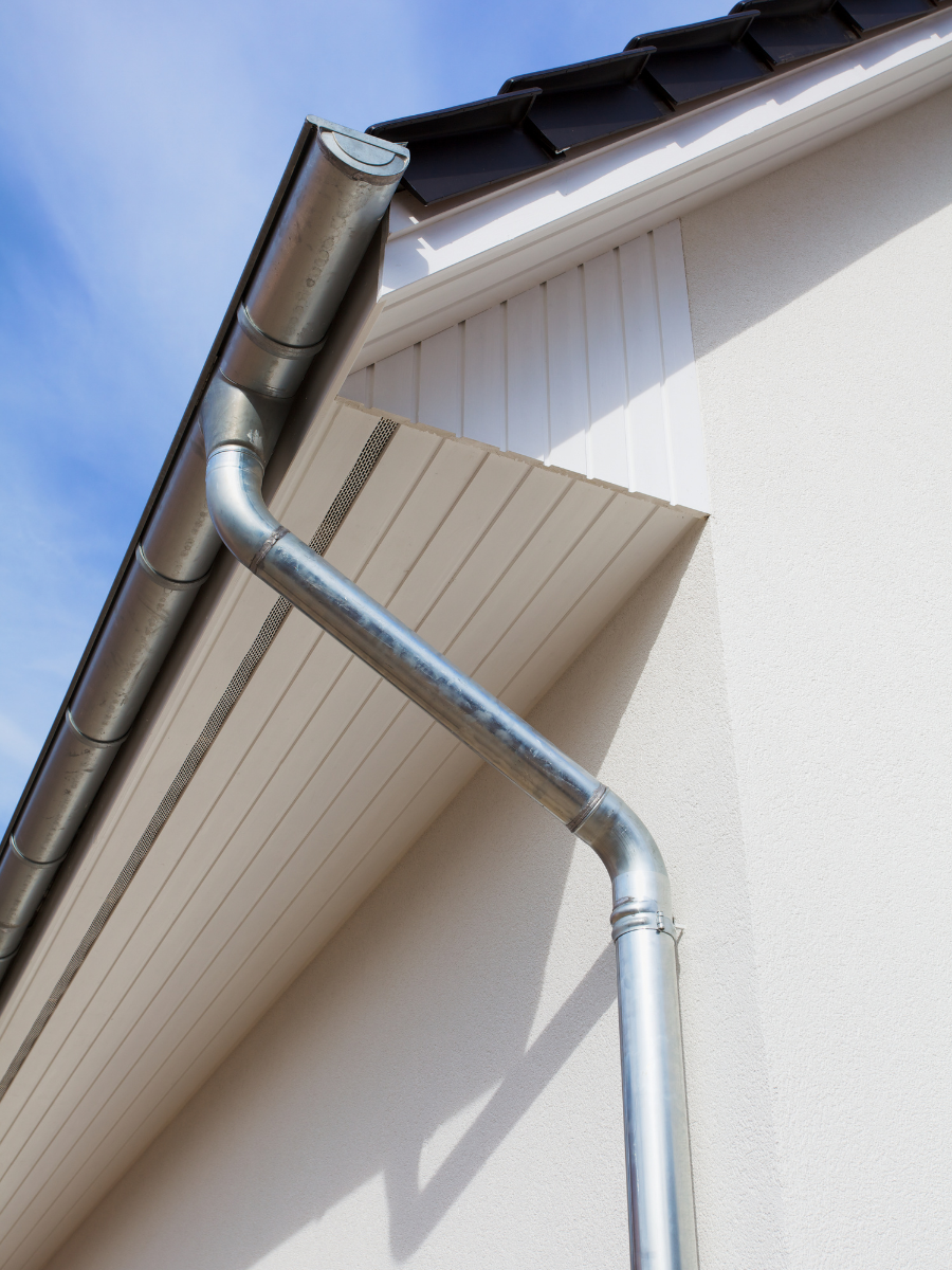 Metal gutter and downspout installed along a residential roofline