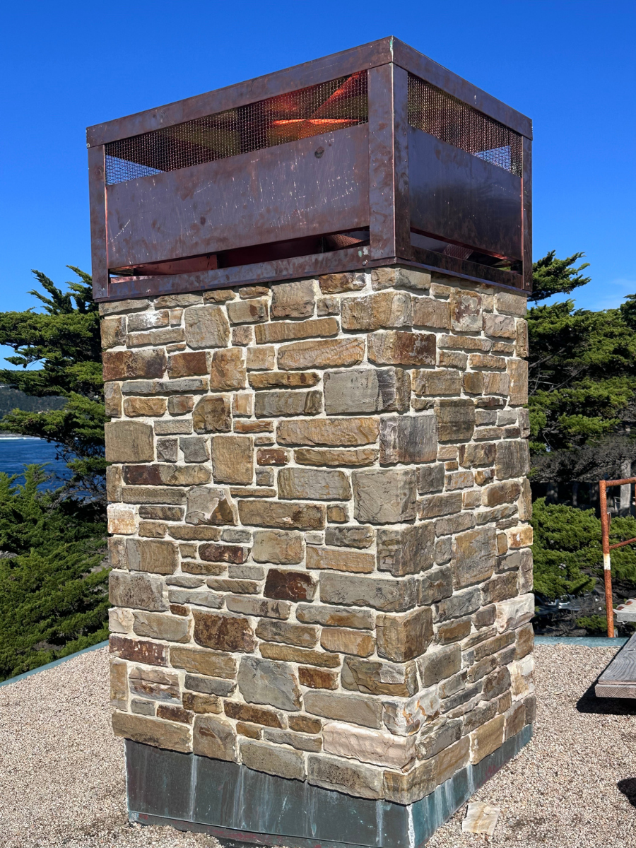 Custom copper chimney cap installed on a stone chimney