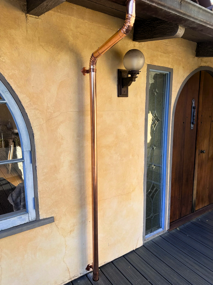 Custom copper downspout installed on a stucco home