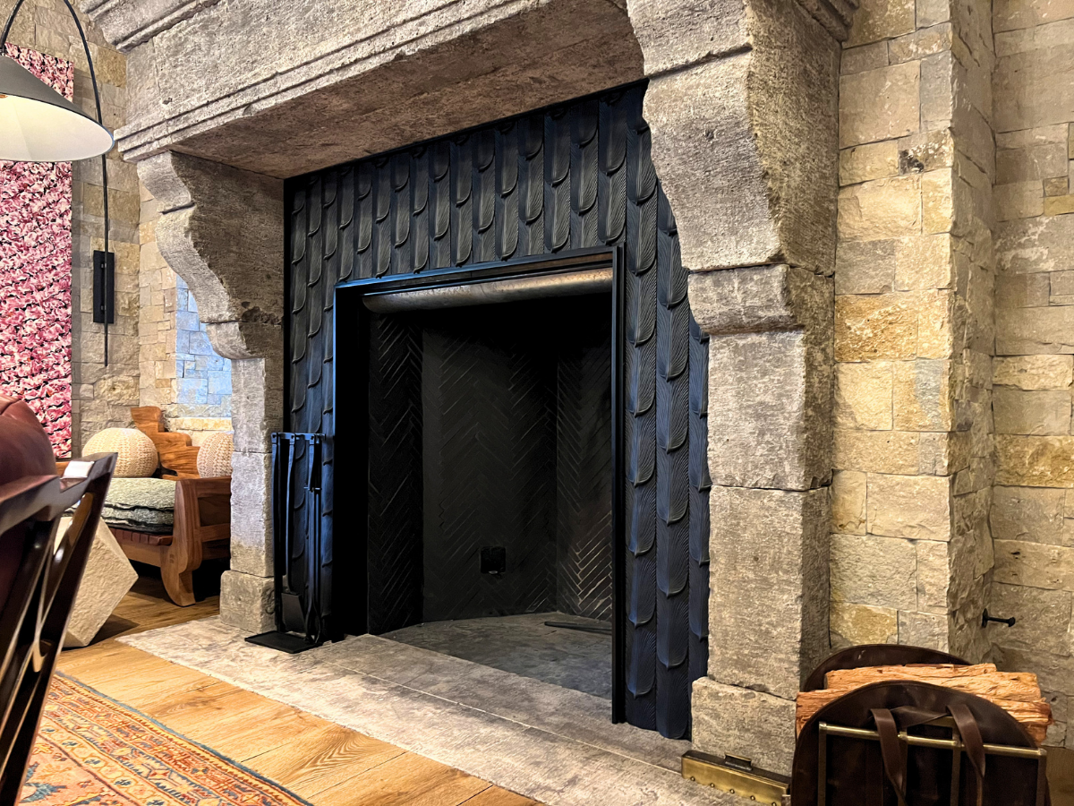Custom black sheet metal fireplace surround installed in a stone fireplace