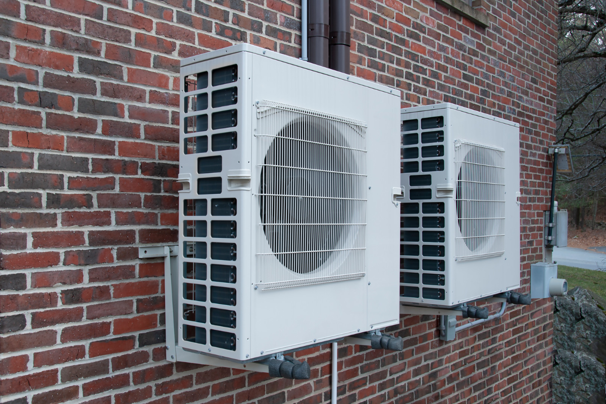 Outdoor residential heat pump unit installed beside a brick home