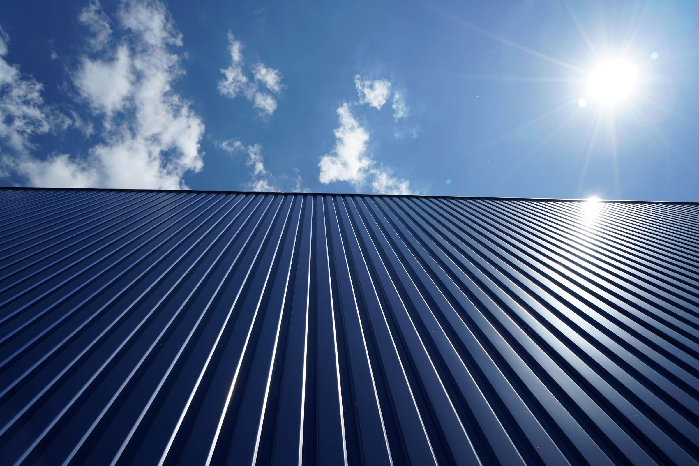 Standing seam metal roof panels reflecting sunlight under a clear blue sky