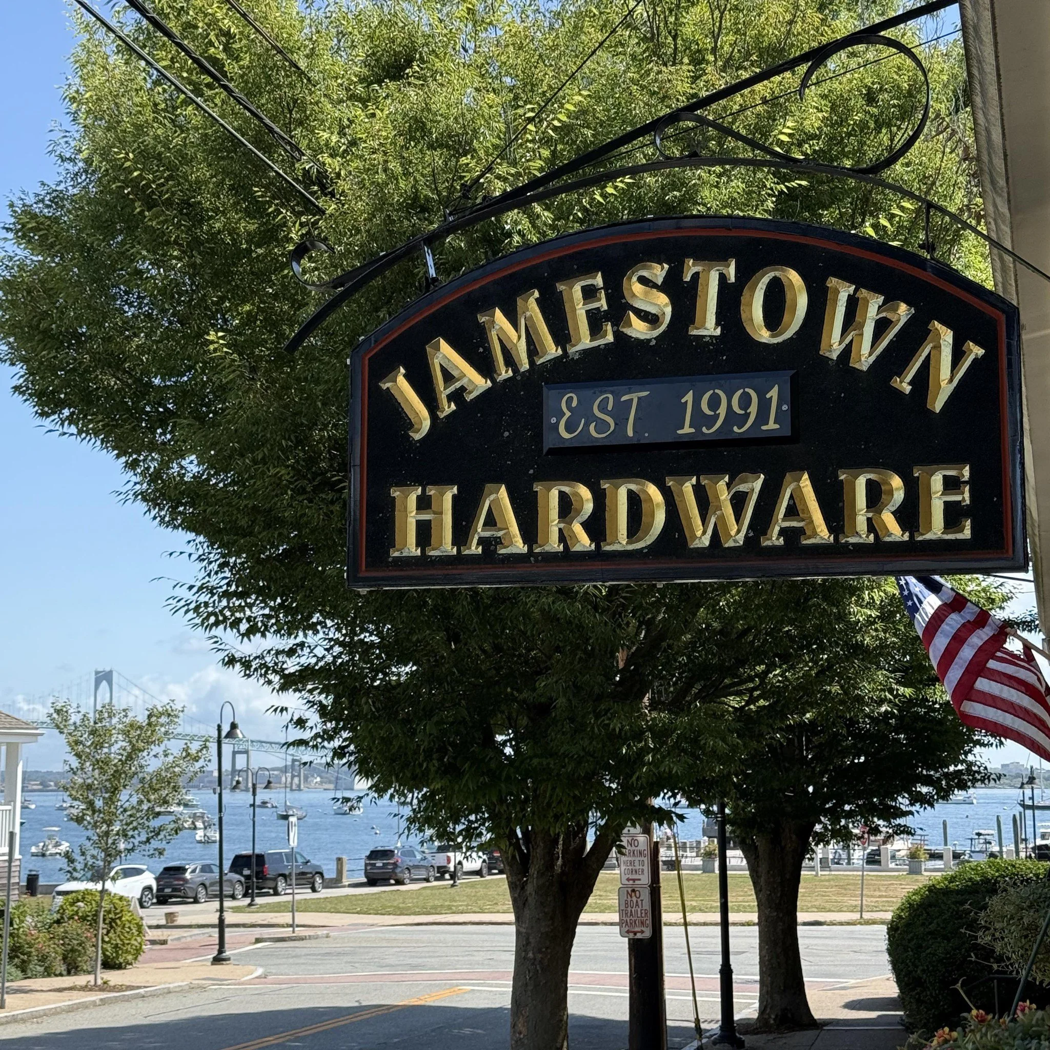 Brian Hamptown Hardware sign with a waterfront view, boats, and the Bay Bridge in the background.