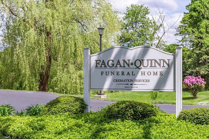 Sign for Fagan-Quinn Funeral Home with greenery and trees in the background.