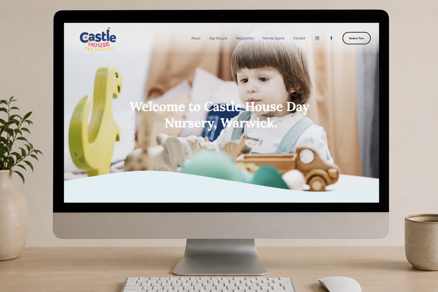 Computer monitor displaying the homepage of Castle House Day Nursery website, showing a young child with brown hair playing with toys.