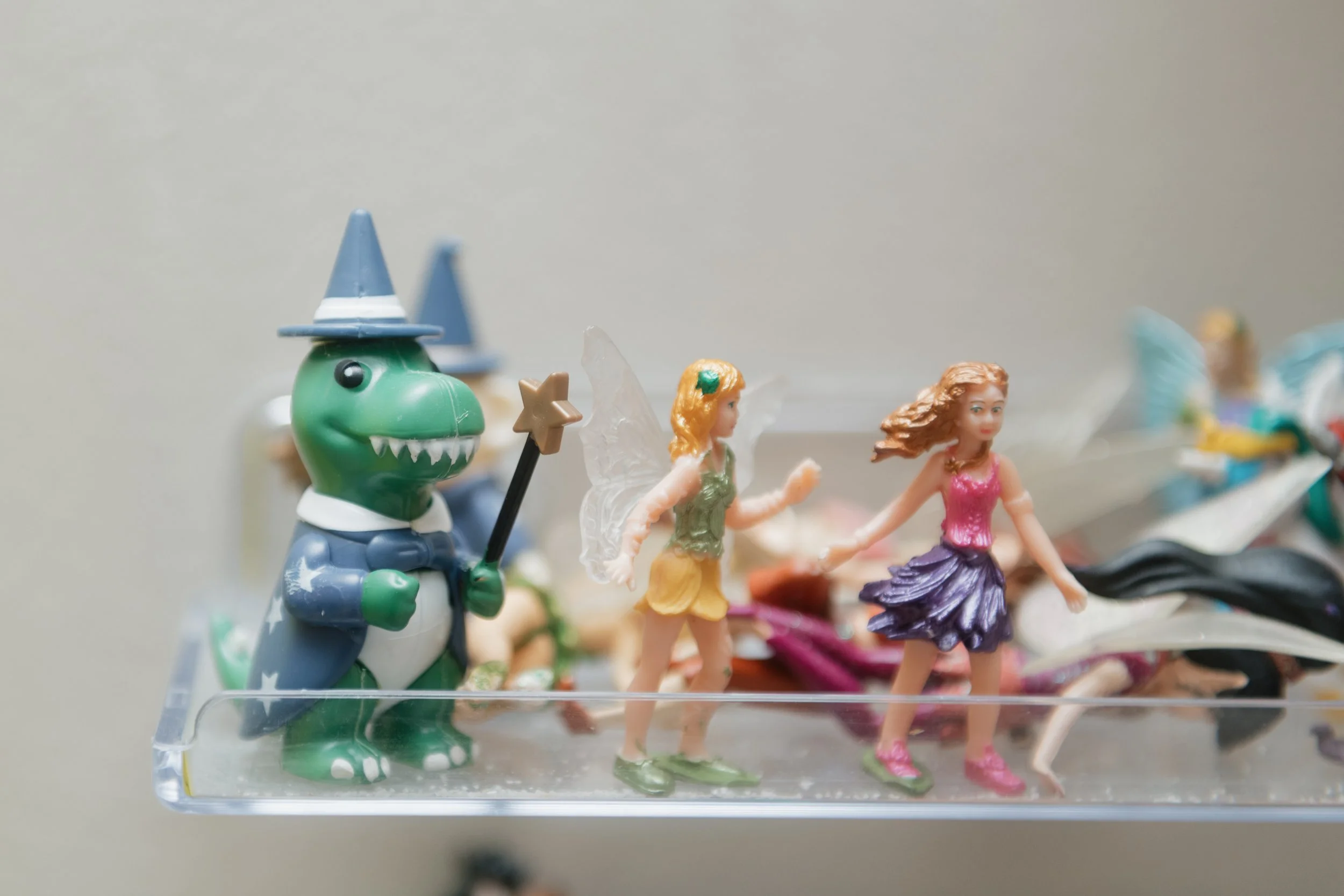 Collection of small figurines including a green dragon wearing a wizard hat, two fairies, and a butterfly