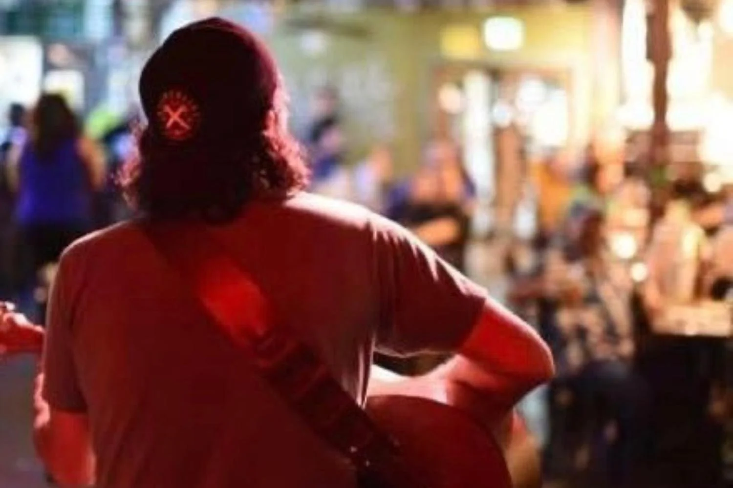 Jaff Jacobs from the back playing n accoustic set in front of a blurred crowd