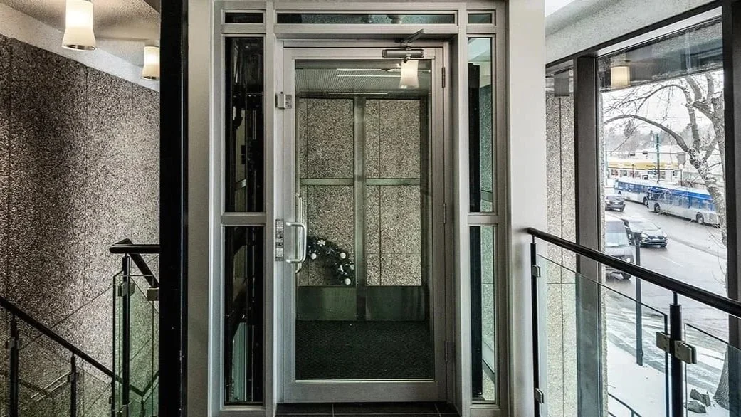 A Butler Mobility - RAM Crystal Elevator in a modern commercial building with staircase to the right