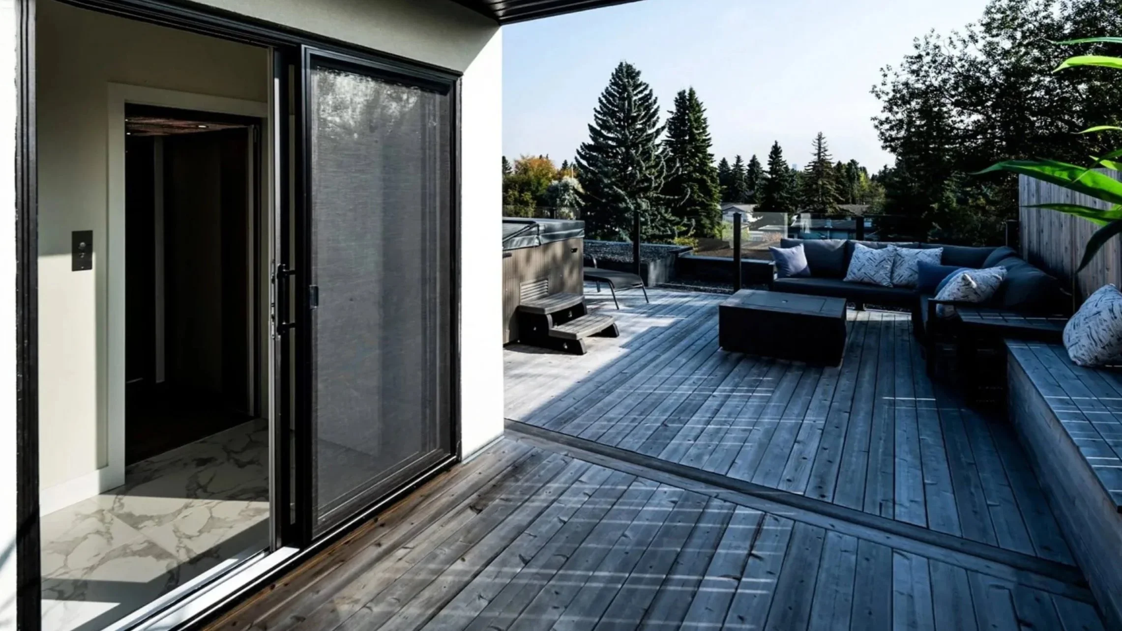 A Butler Mobility - RAM Crystal Elevator opens up to a wooden roof top deck patio