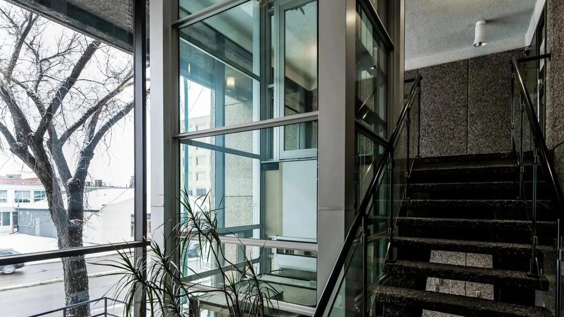 A Butler Mobility - RAM Crystal Elevator in a modern commercial building with staircase to the right