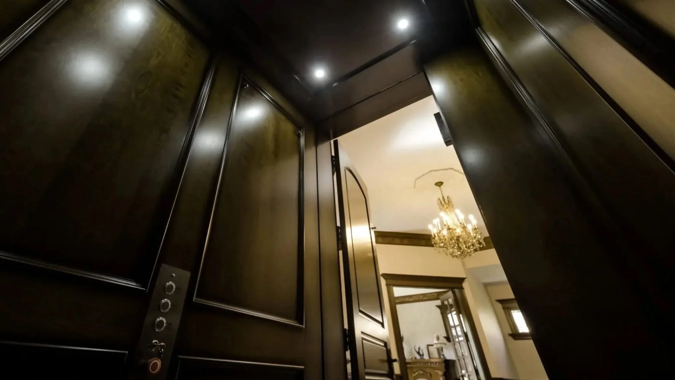 A Butler Mobility - RAM Crystal Elevator interior featuring dark wood walls looking out into a residential hallway