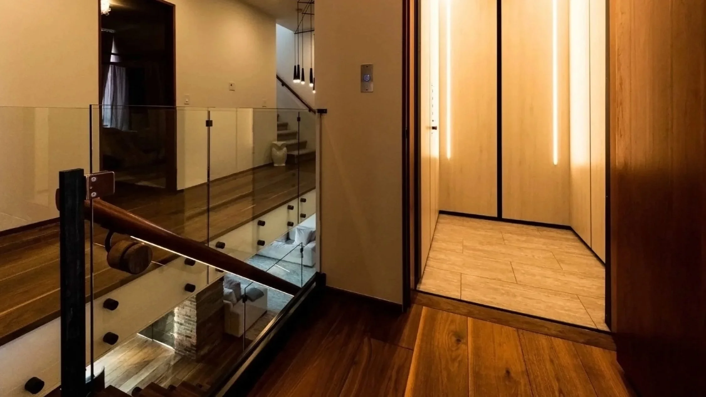 A Butler Mobility - RAM Crystal Elevator with white walls and well lit interior of elevator in a residential home featuring warm lighting