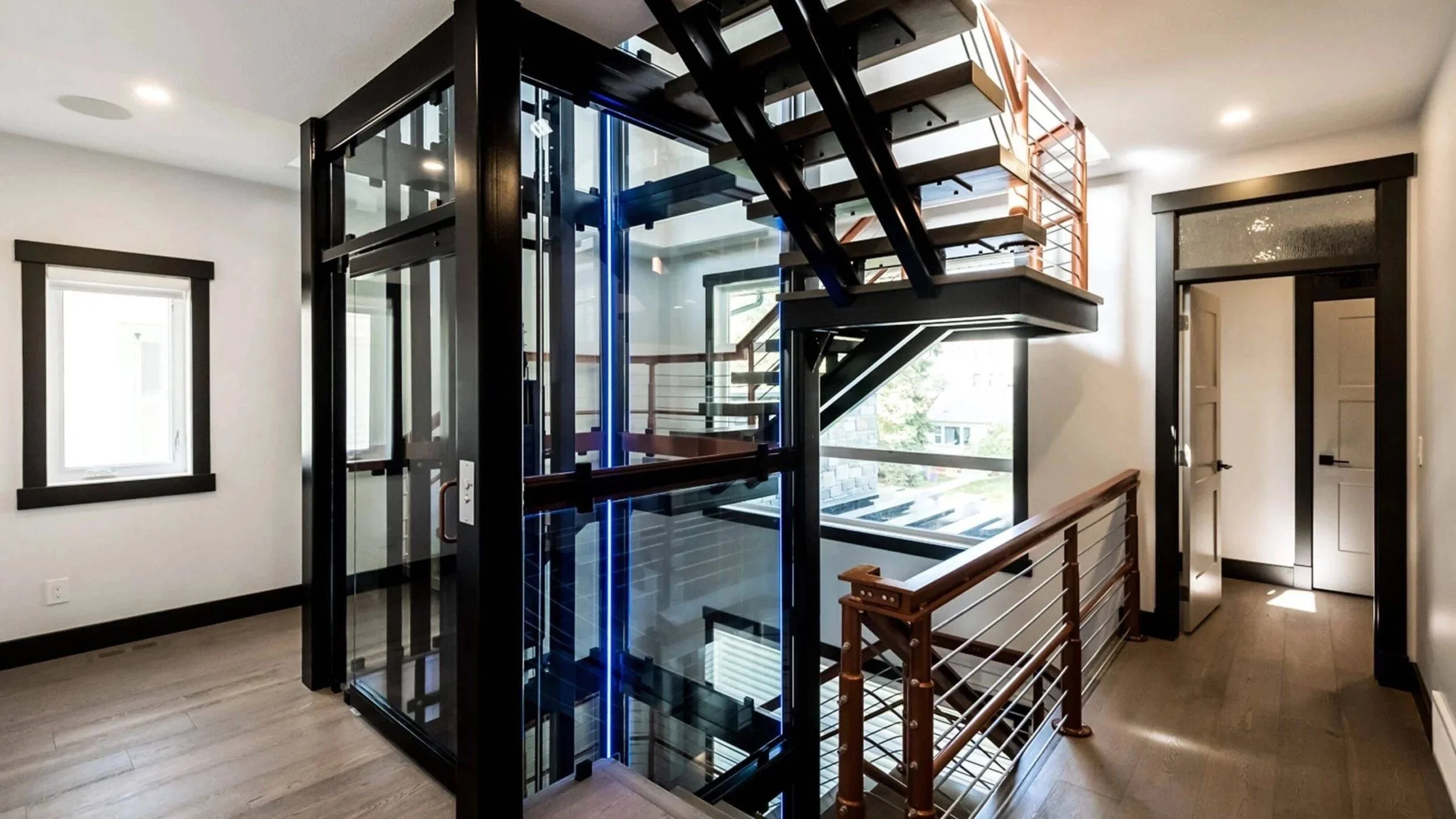 A Butler Mobility - RAM Crystal Elevator featuring a modern staircase and a clear elevator