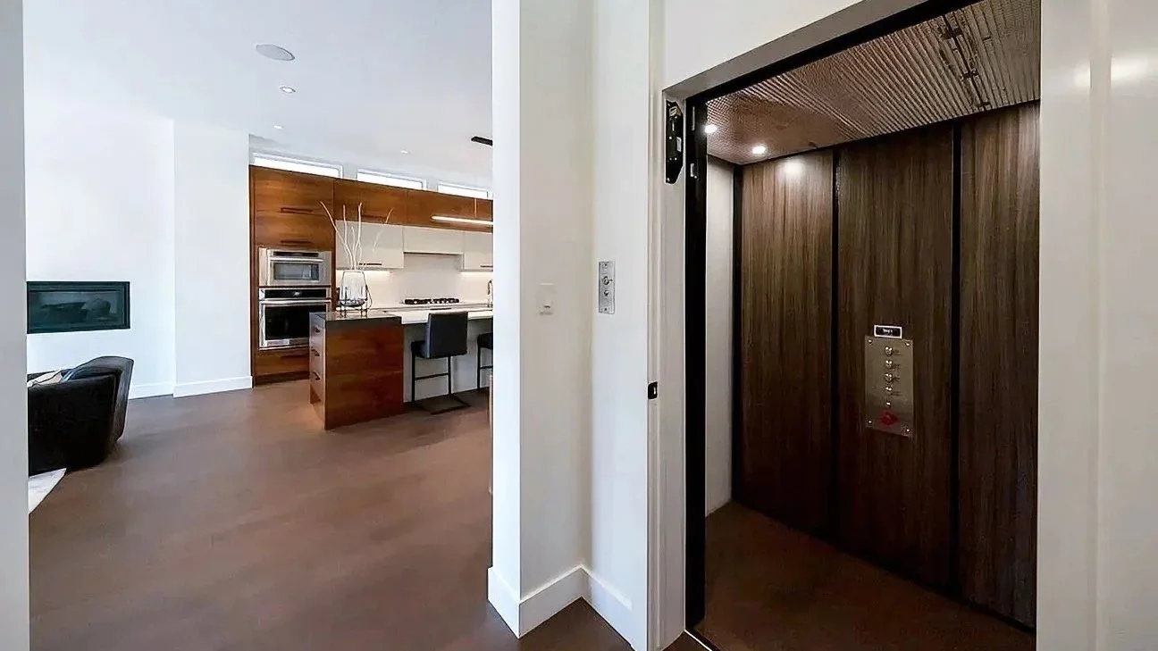 A Butler Mobility - RAM Crystal Elevator in a modern residential home with a kitchen in the background