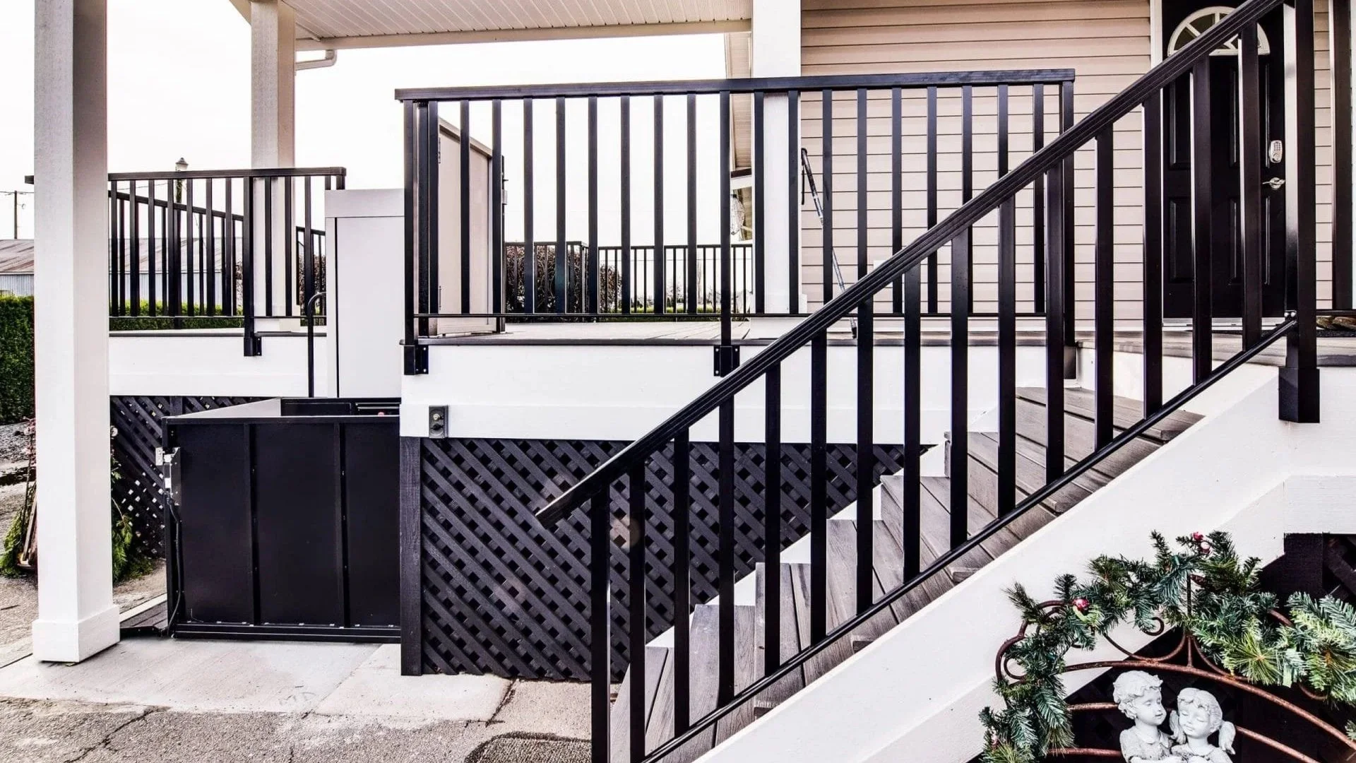 A Butler Mobility RAM Trus-T vertical platform lift is next to staircase leading to a residential porch