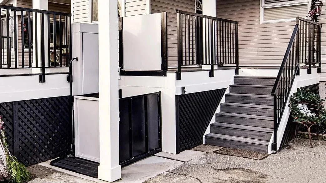 A Butler Mobility RAM Trus-T vertical platform lift is next to staircase leading to a residential porch