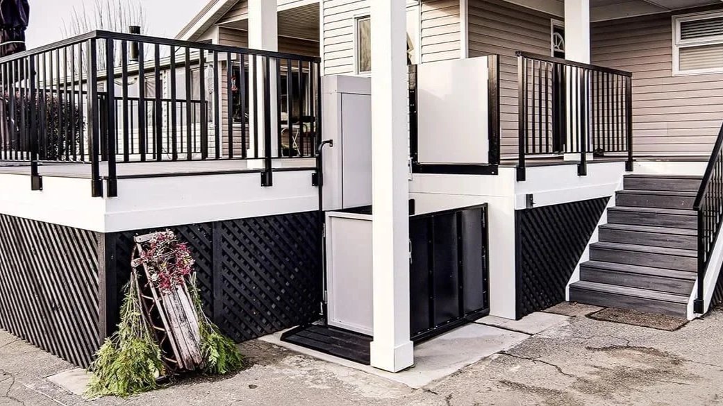 A Butler Mobility RAM Trus-T vertical platform lift is next to staircase leading to a residential porch