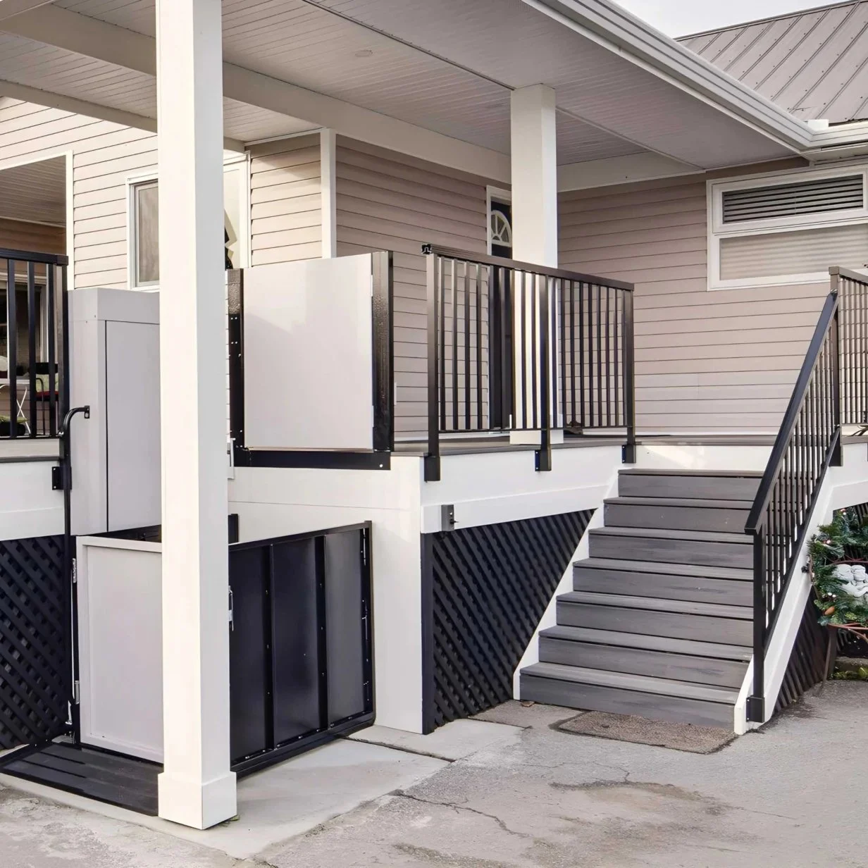 Featuring a Butler Mobility RAM Trus-T vertical platform lift installed on the porch of a residential home with staircase on right