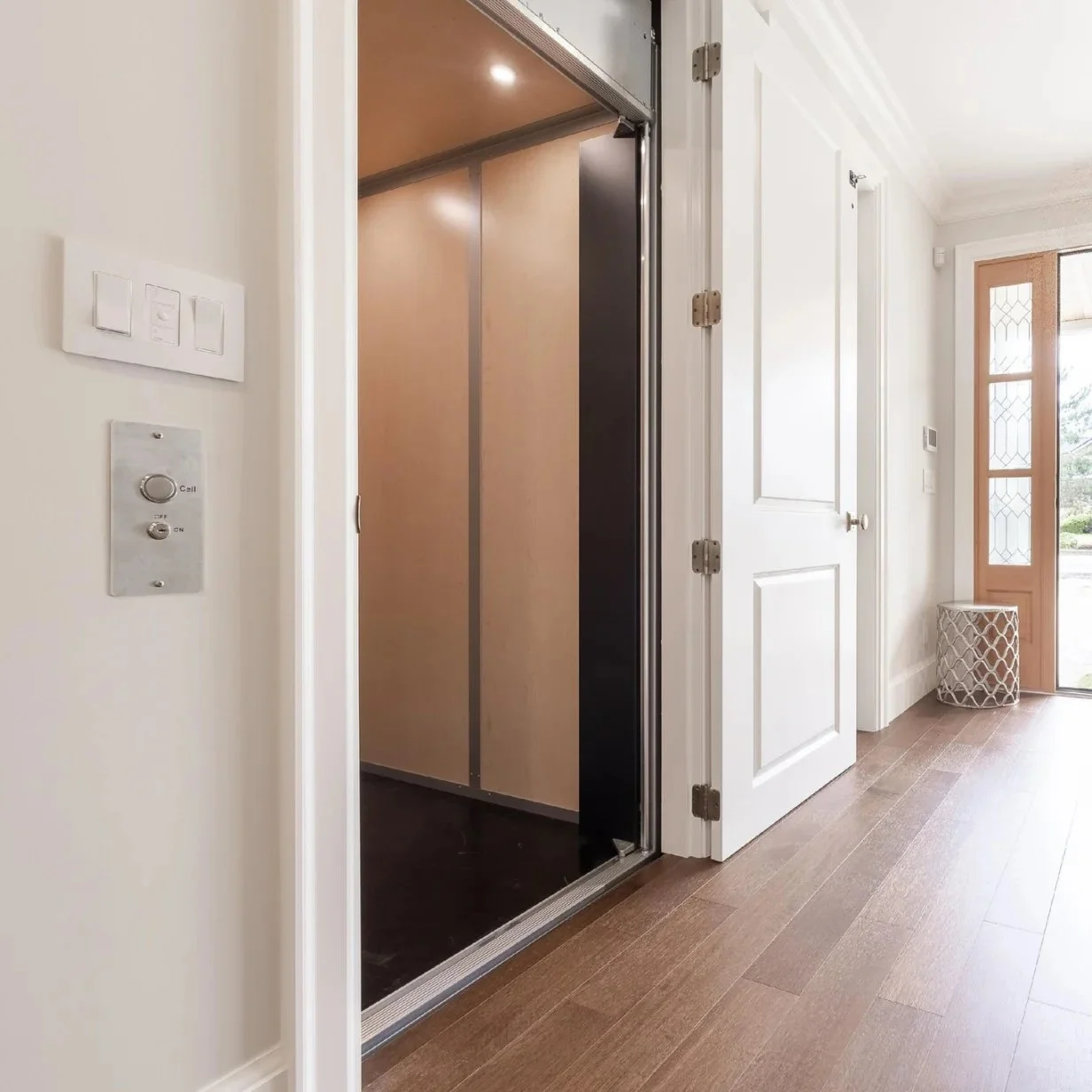 An interior view of a Butler Mobility - RAM elevator in a brightly lit home with a white door