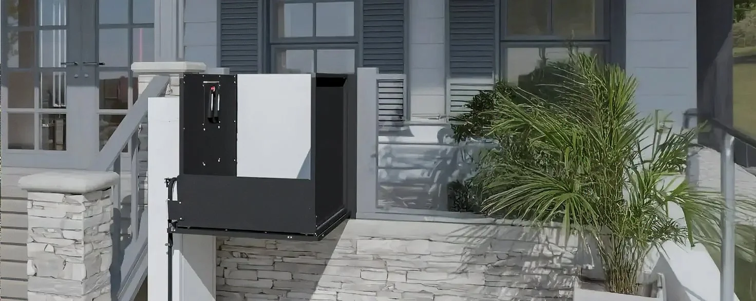 A Butler Mobility RAM vertical inclined platform lift in front of a porch and staircase to a home