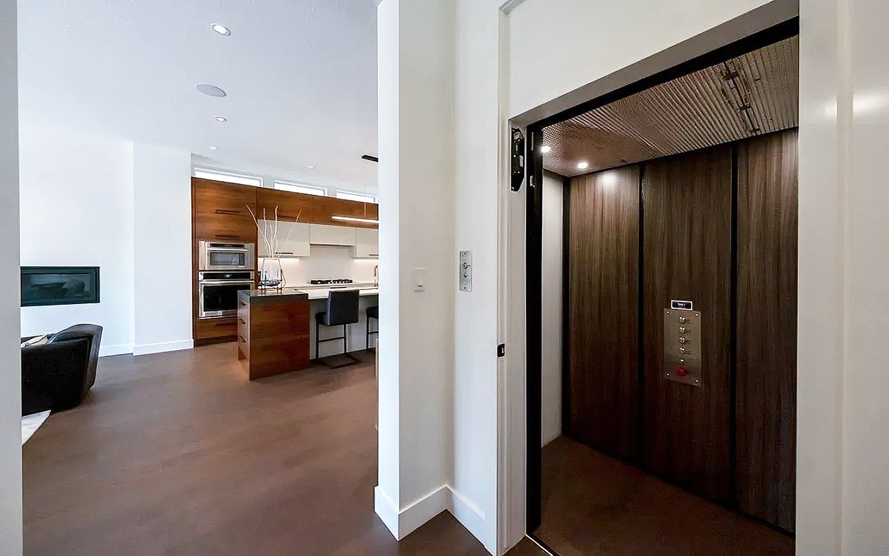 Features a Butler Mobility home elevator in right corner and kitchen in the background