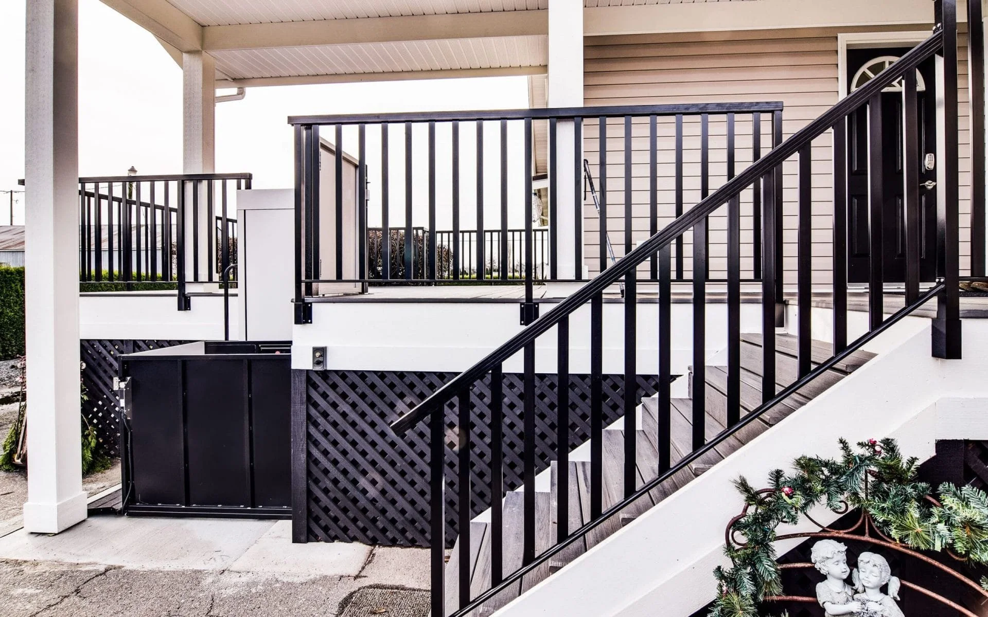 A Butler Mobility RAM Trus-T vertical platform lift is next to staircase leading to a residential porch