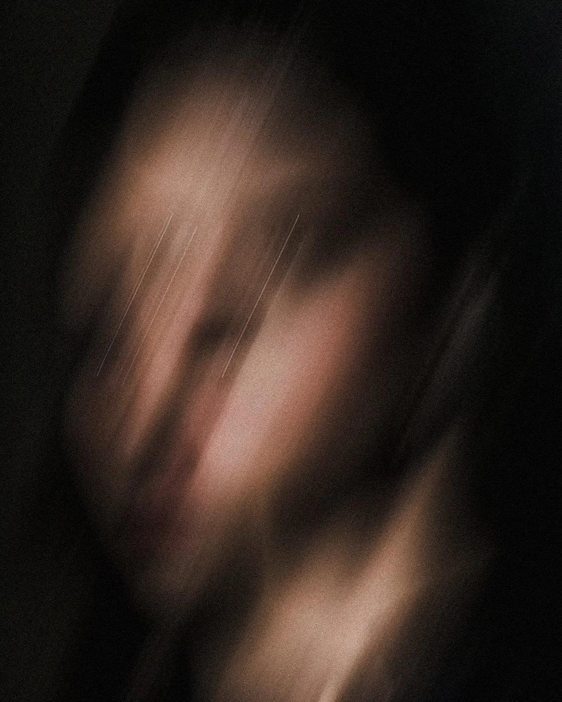 Imagen muy borrosa y oscura de una persona con cabello oscuro y piel clara, sin detalles claros debido a la falta de nitidez.