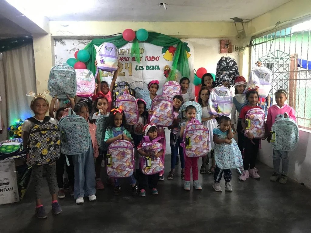 Girls receiving donated backpacks.