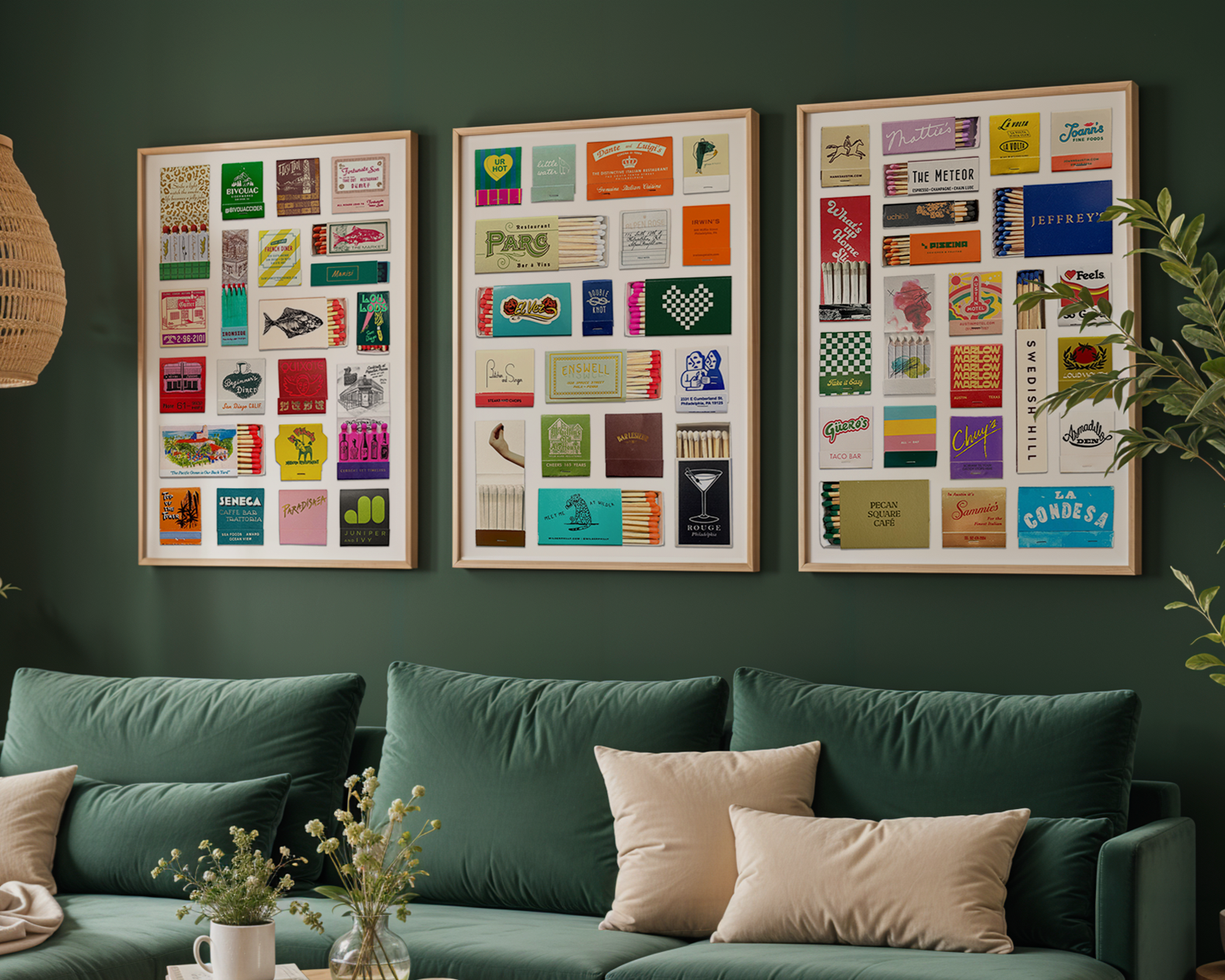 Three framed displays of colorful matchboxes and matchbook covers hung on a green wall above a sofa with beige and green cushions, next to a potted plant.