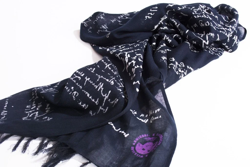 A black silk scarf with white handwritten script and a purple heart logo featuring a bear face.