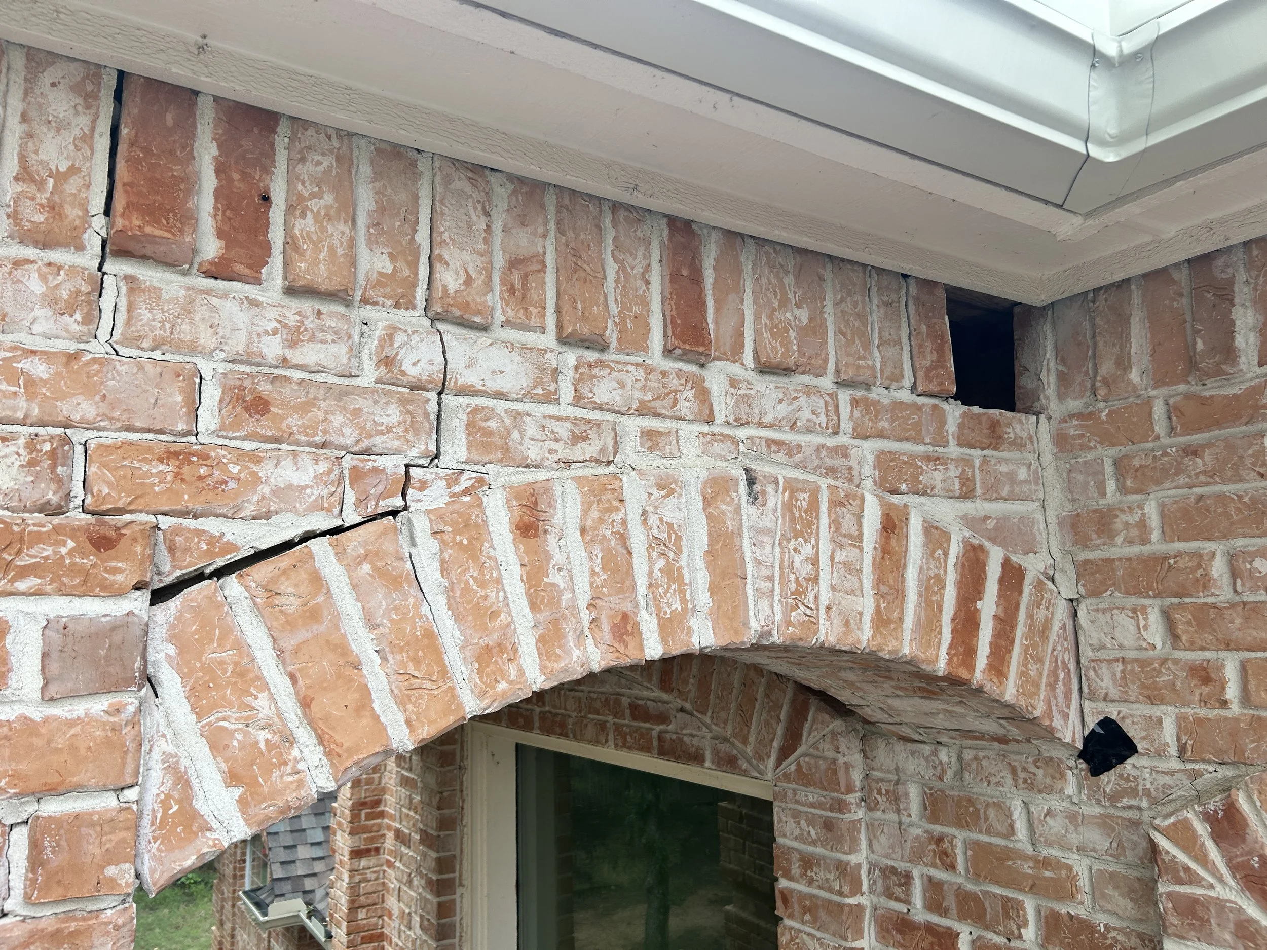 Severe brick archway cracking and masonry separation above exterior opening