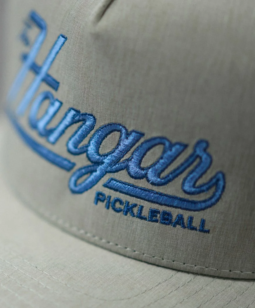 Close-up of a gray hat with blue embroidered text reading "Hangar Pickleball."