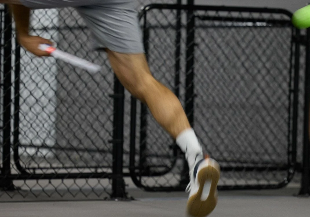Close-up of a person running on a treadmill, focusing on their legs and shoes.