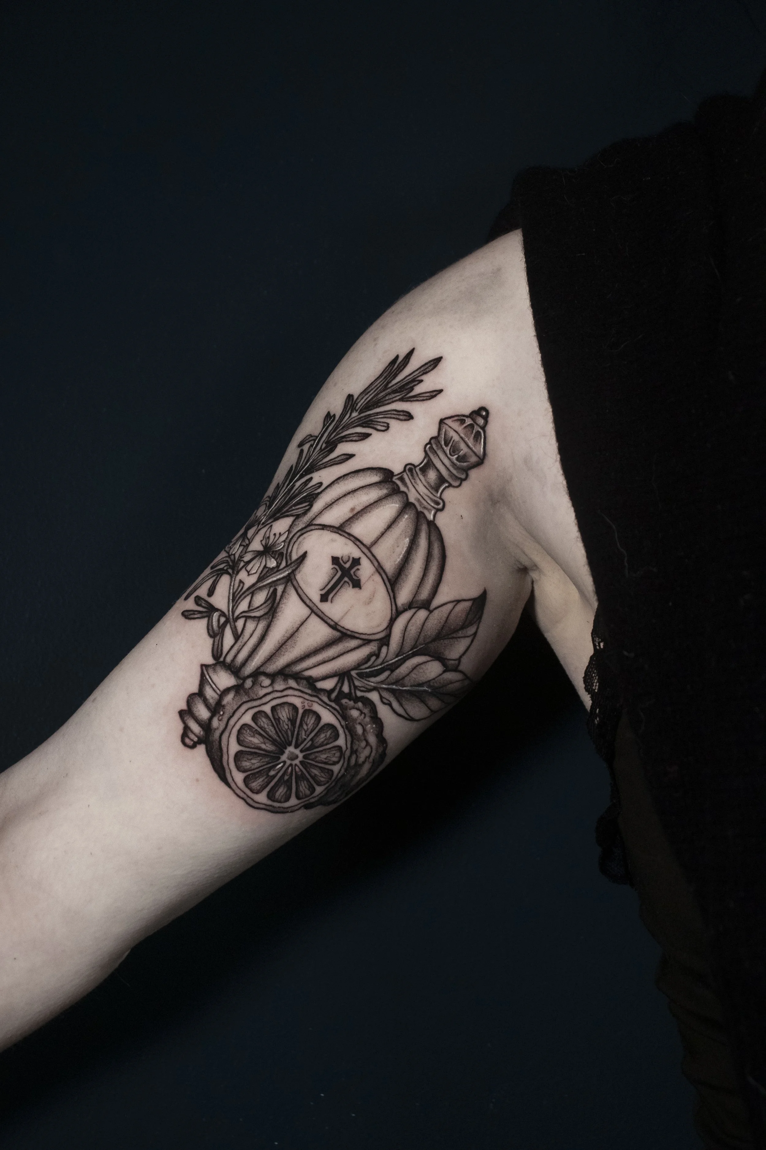 Black and grey potion bottle of holy water surrounded by rosemary and bergamot