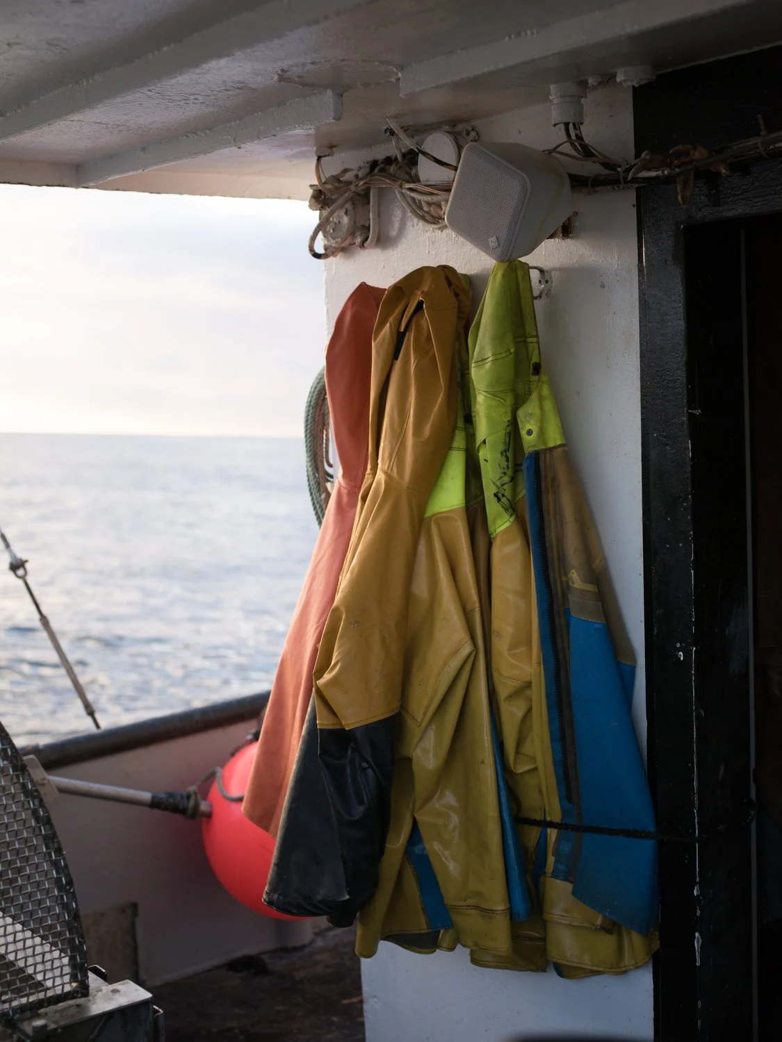 brightly colored fishing jackets hanging on a boat