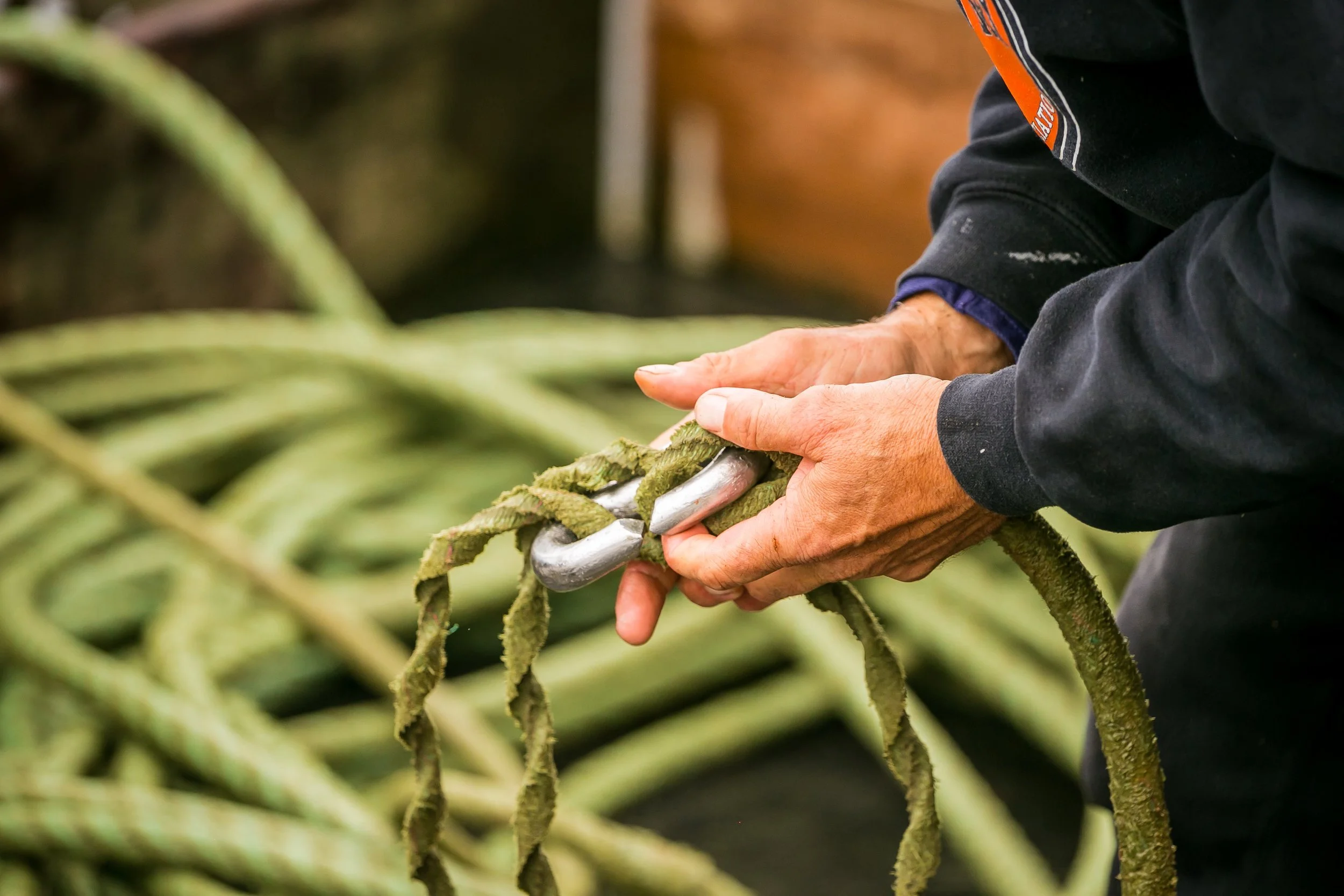 Close up of a fisherman's hands on a shackle and a rope