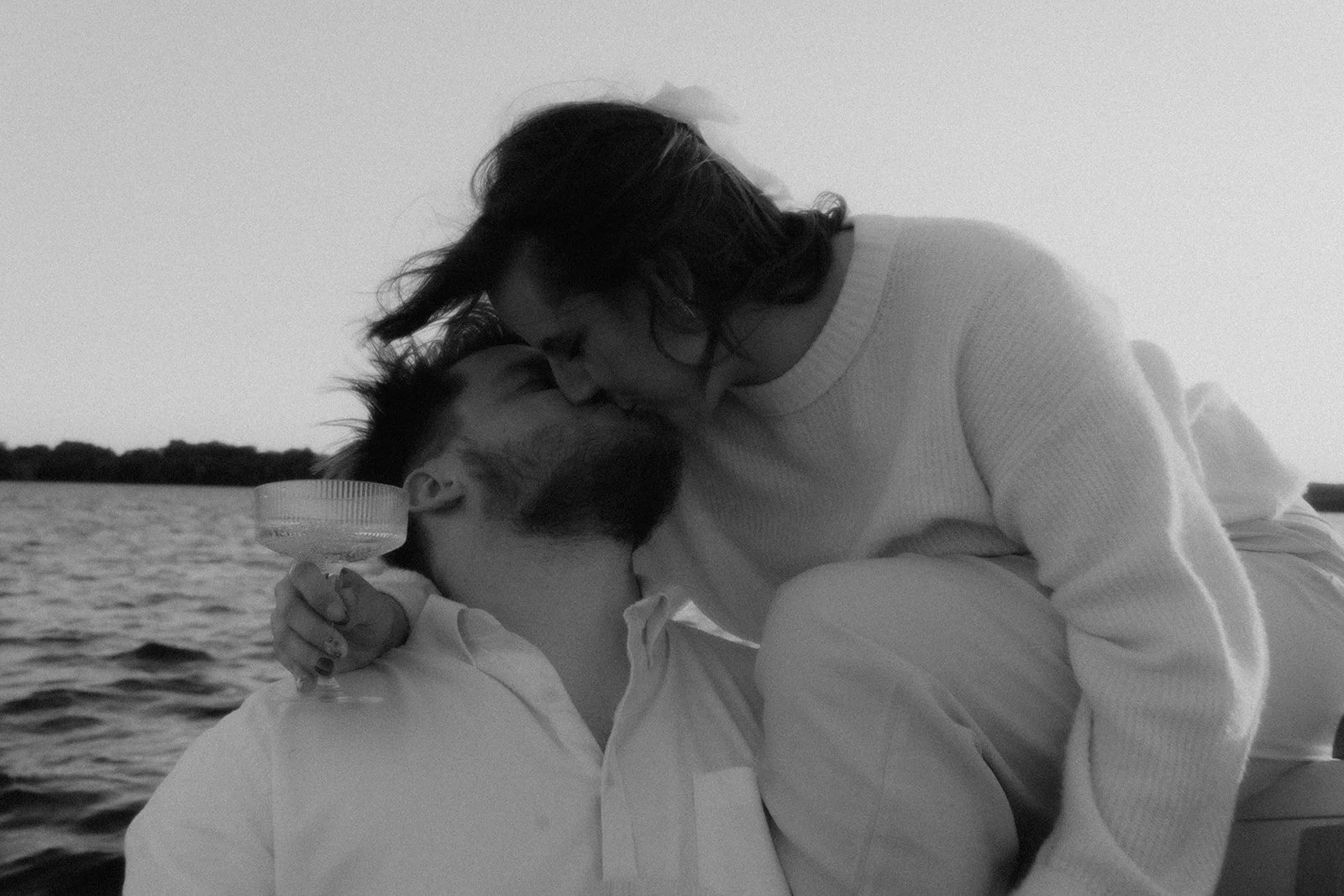 Couple in black and white kisses on a sailboat in Nashville, TN.