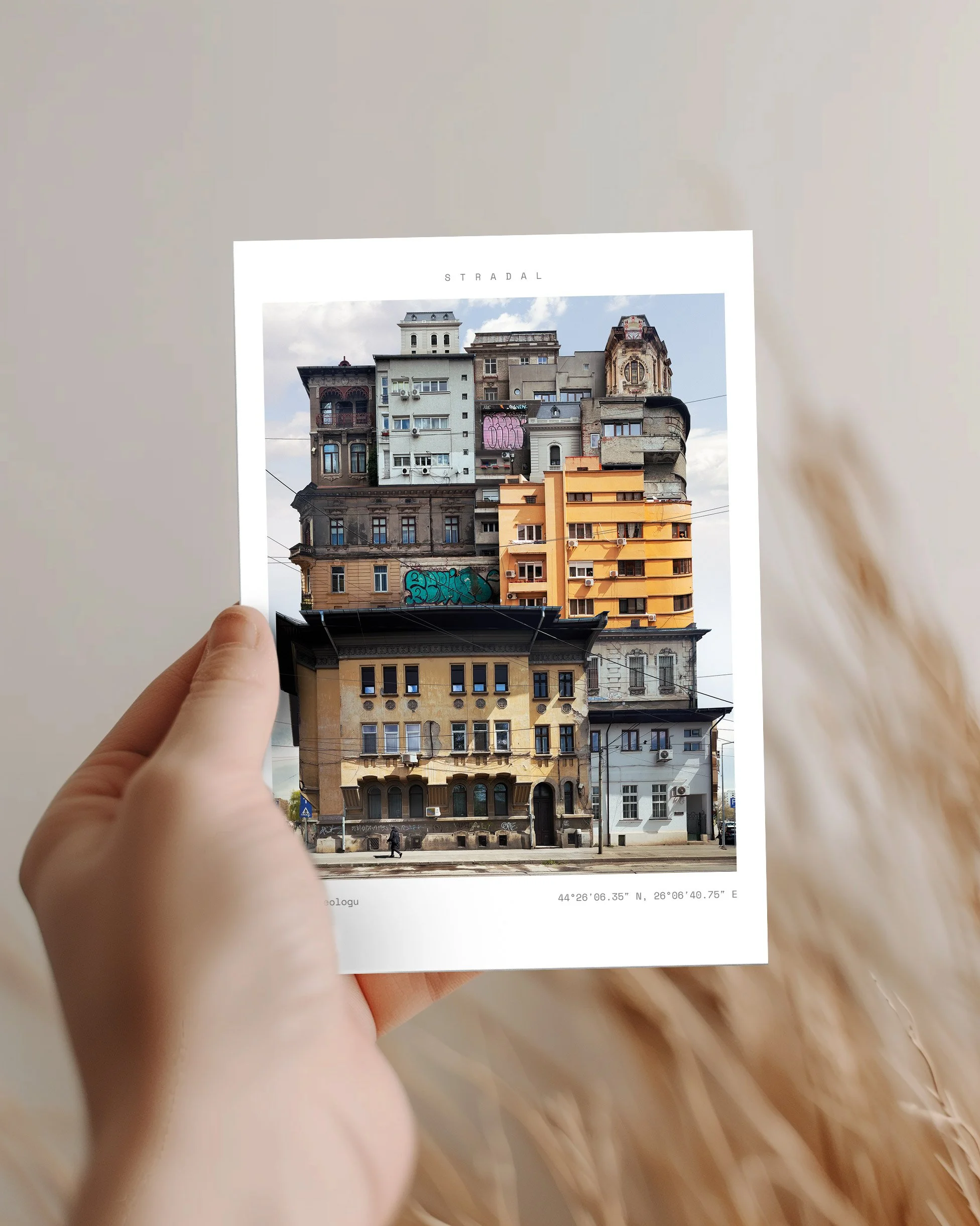 Photograph of a person holding a printed photo of a building with eclectic architecture, graffiti, and multiple stories against a blurred background.