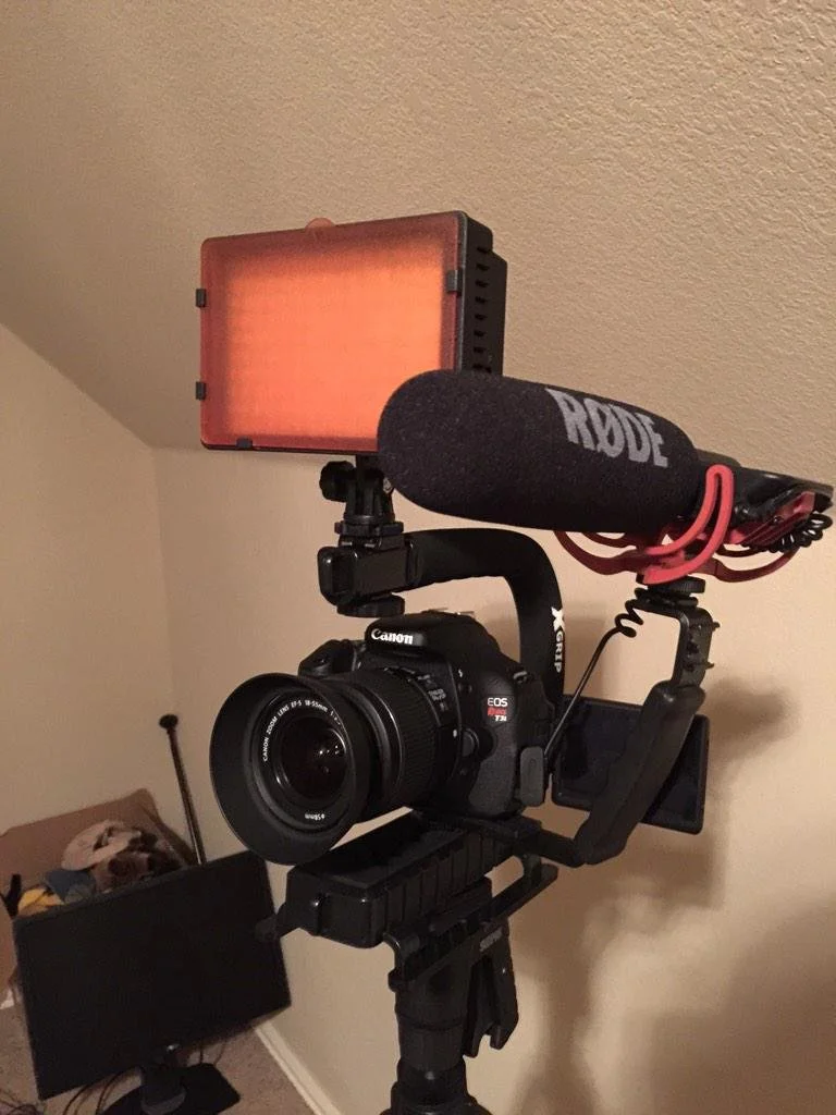 Camera mounted on a stabilizer rig with a microphone and a light attached.