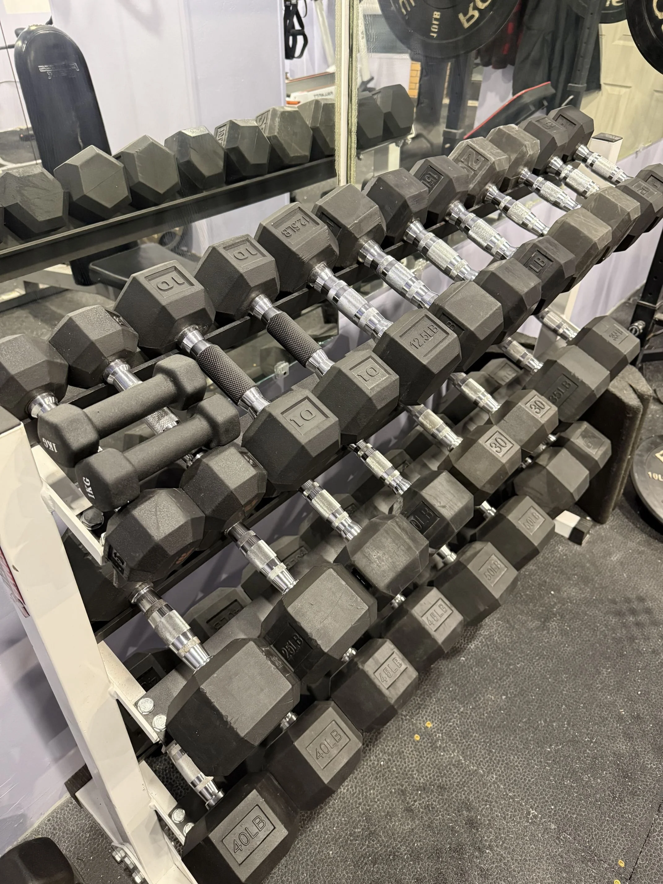 A set of adjustable dumbbells with hexagonal weights arranged on a rack in a gym.