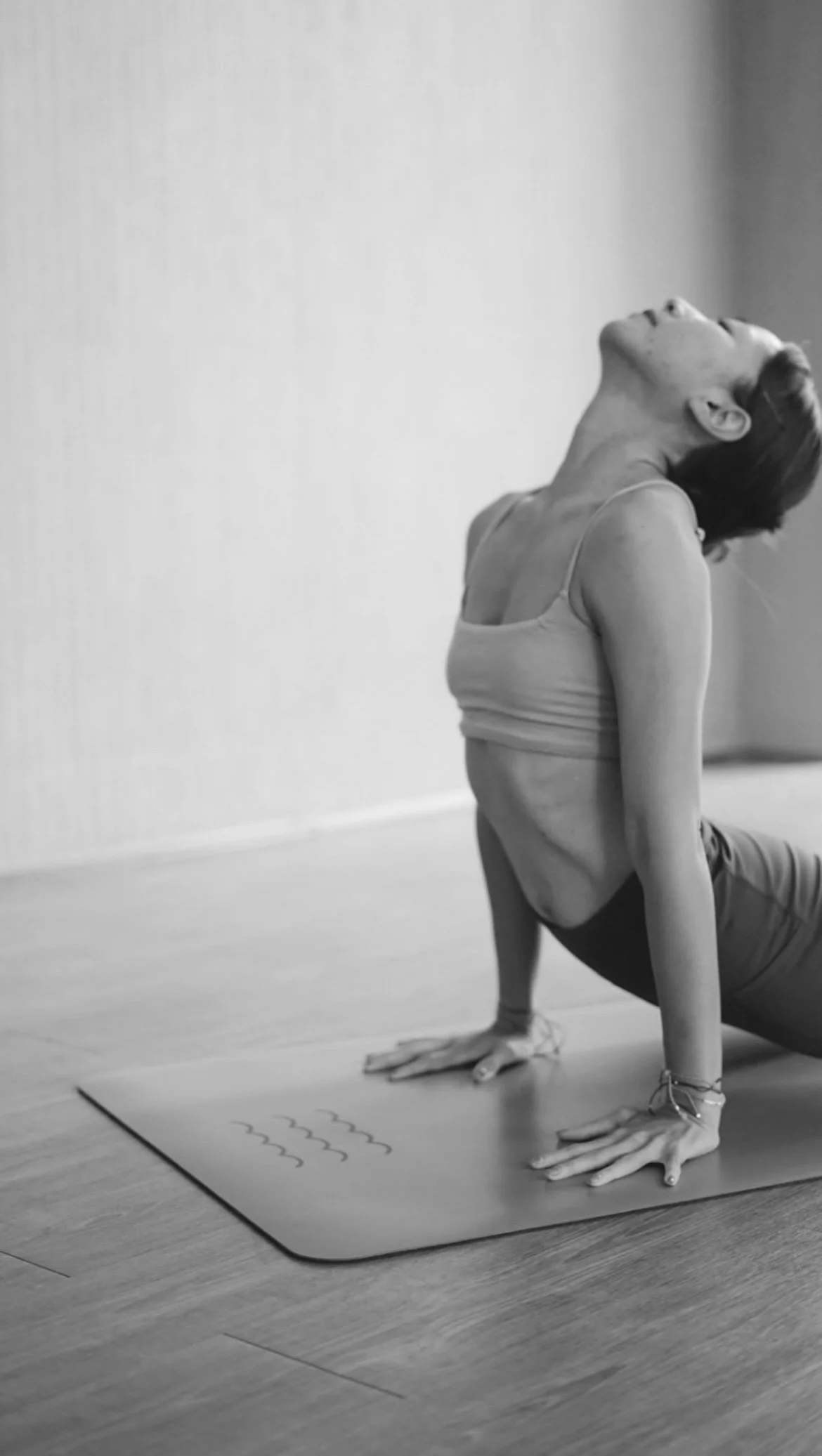 Woman performing yoga upward-facing dog pose on a mat in a studio.