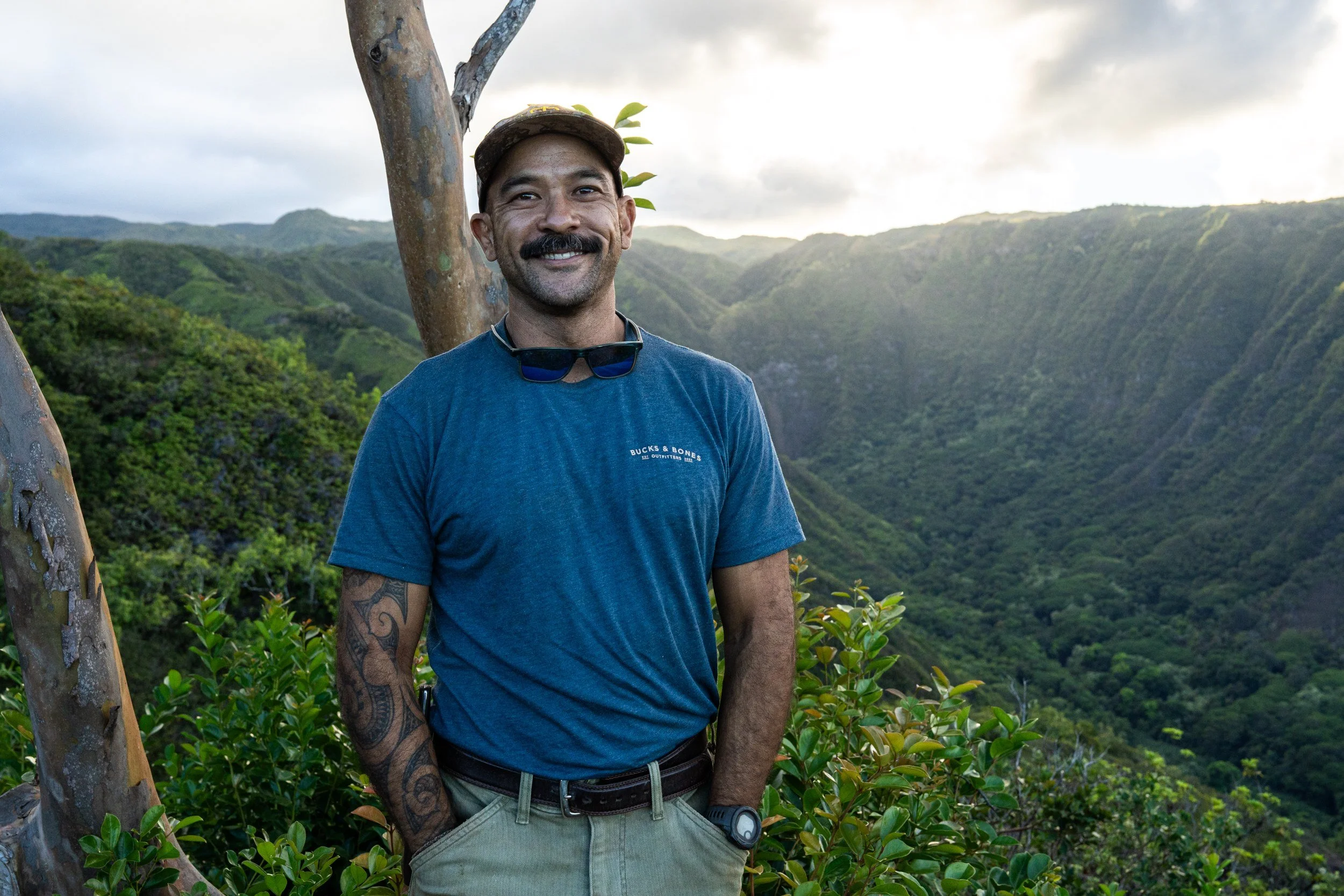 Josiah Ching, Native Hawaiian veteran and Bucks & Bones guide, standing at an overlook with the lush Molokai valley in the background.