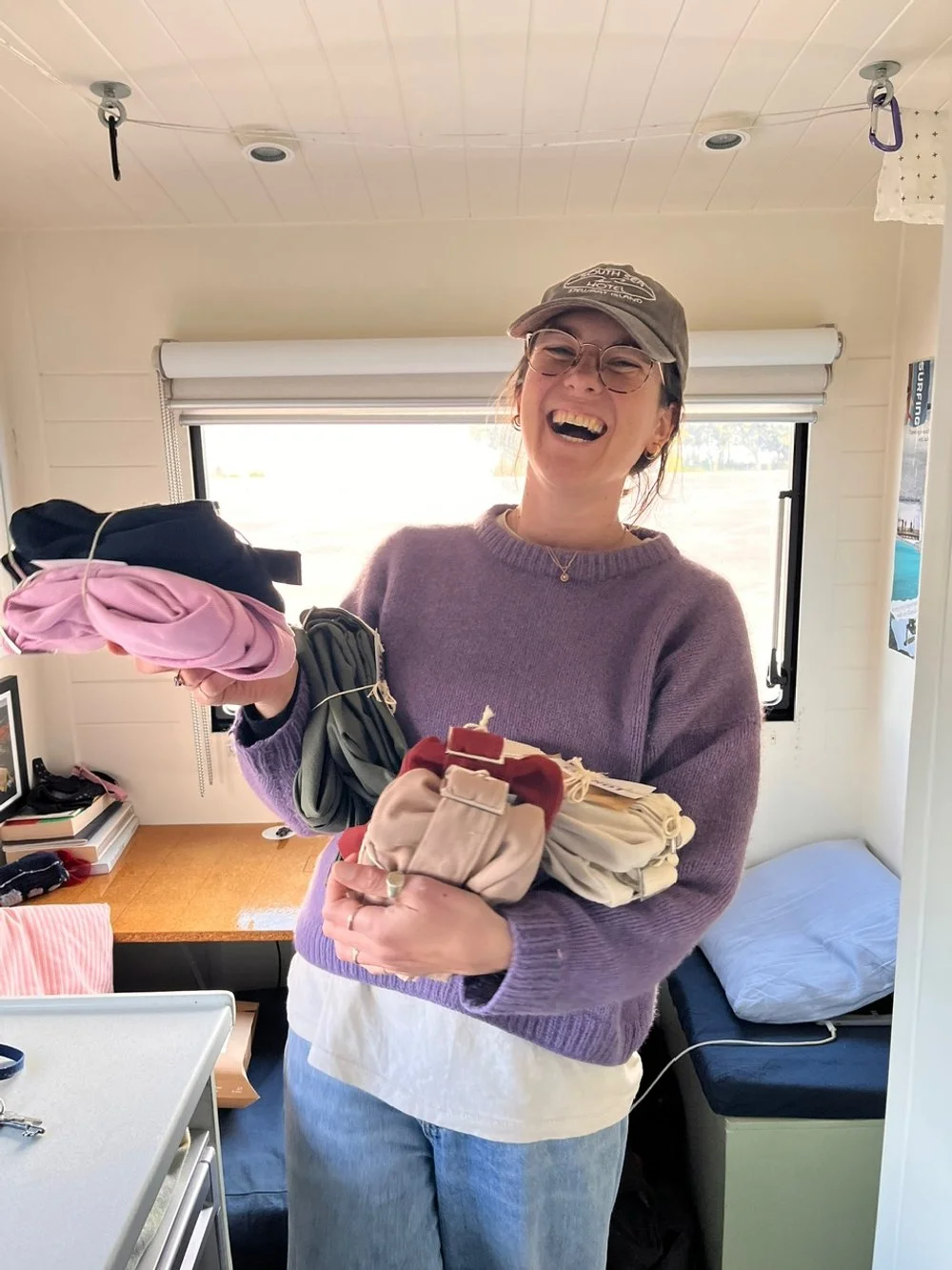 The sewer of Longies handmade denim crossbody bags smiling, holding a lot of orders ready to be sent to her customers.