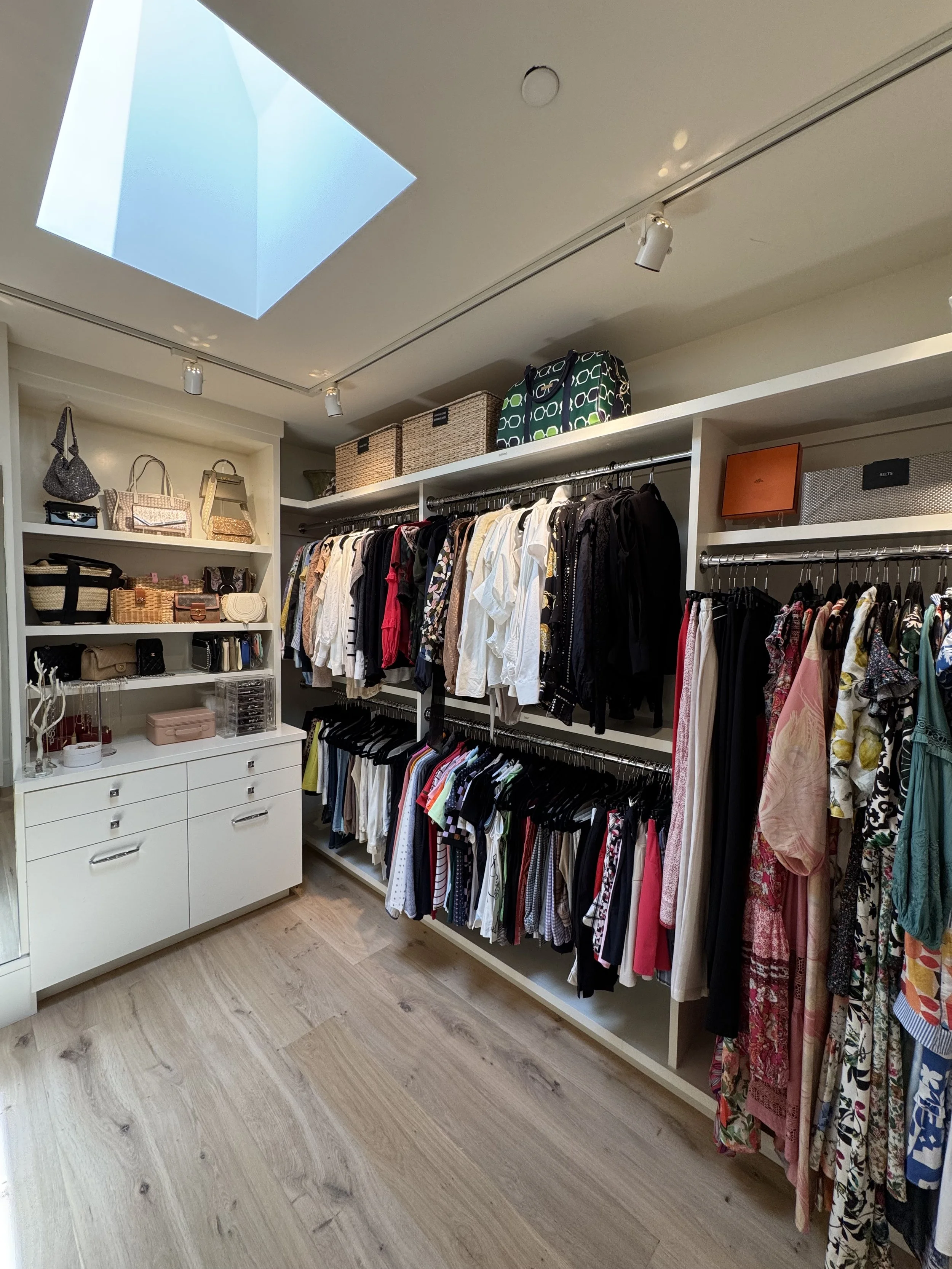 A large walk in closet with women's clothing and accessories