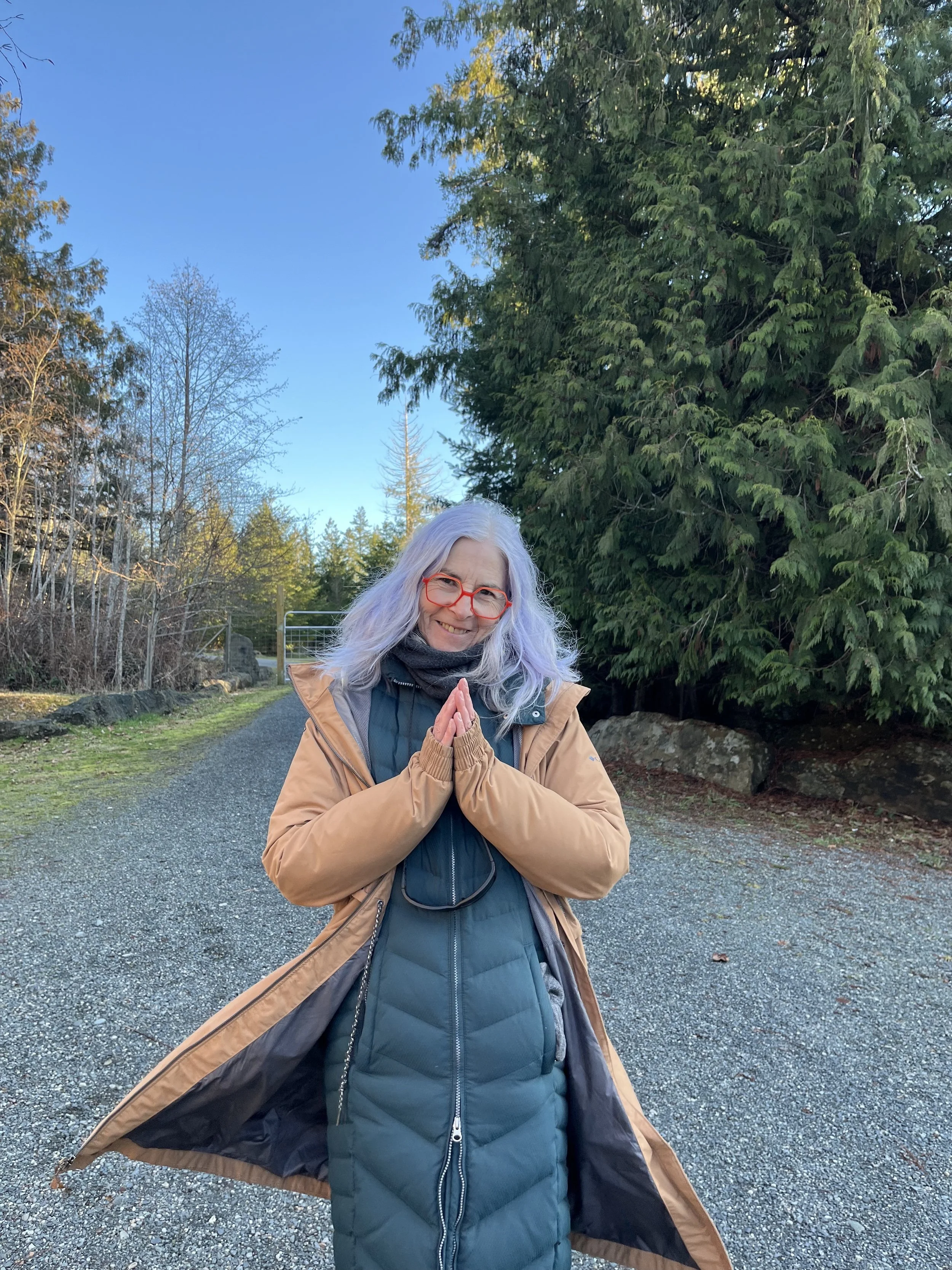 photo of the artist, gray hair, brown jack doing a prayer movement