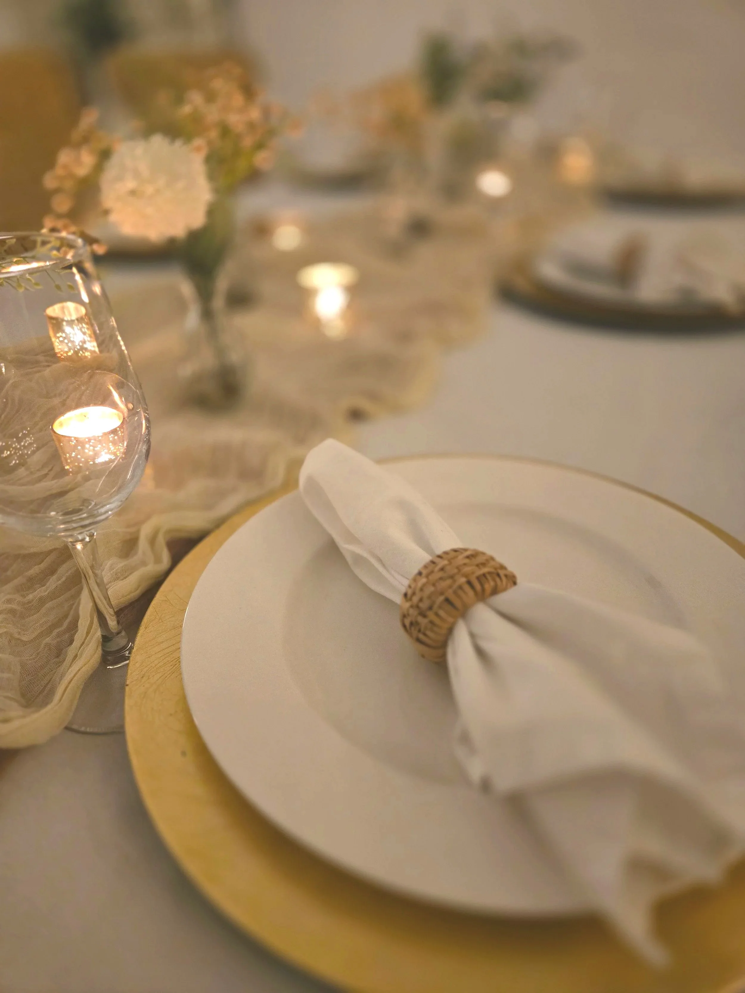 White plate on wicker charger with candles at Oasis Events Collective in Sarasota, FL