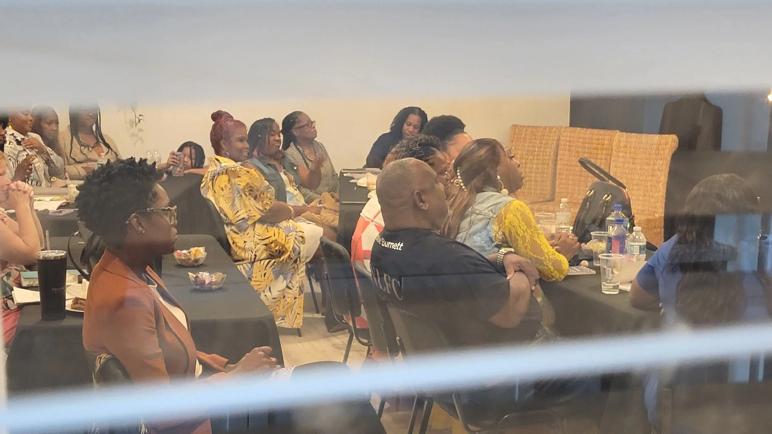 People sitting at tables in a conference room watching a presentation or speaker.