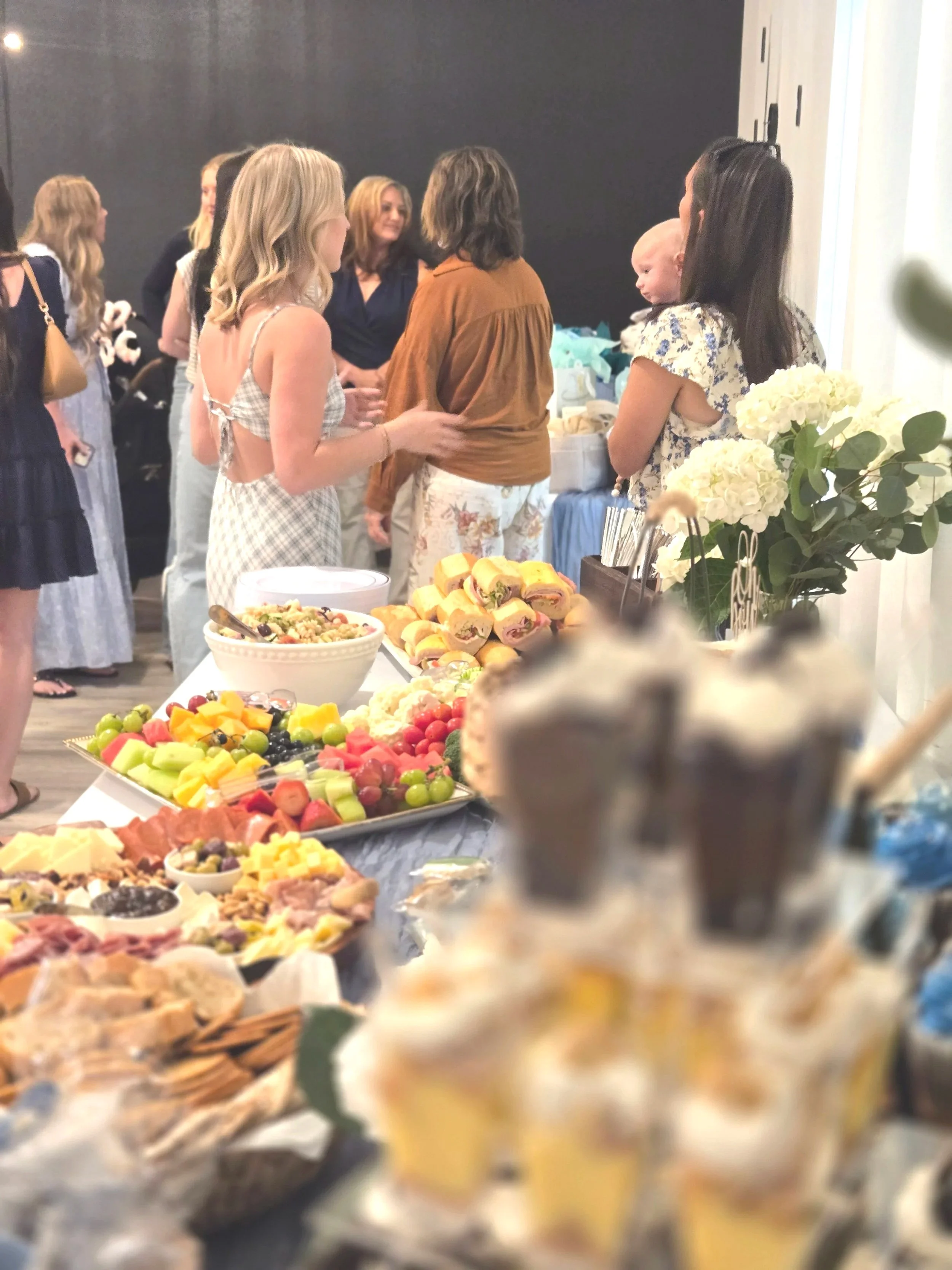 Guests and a beautiful food table at a baby shower at Oasis Events in Sarasota Florida.  An event venue for bridal showers, birthday parties and corporate meetings near Lakewood Ranch, Venice and Parrish